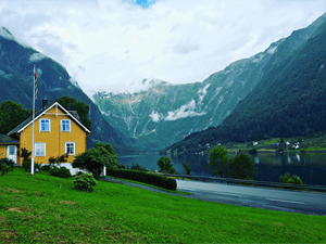 Gult hus med norsk flagg og fjellandskap
